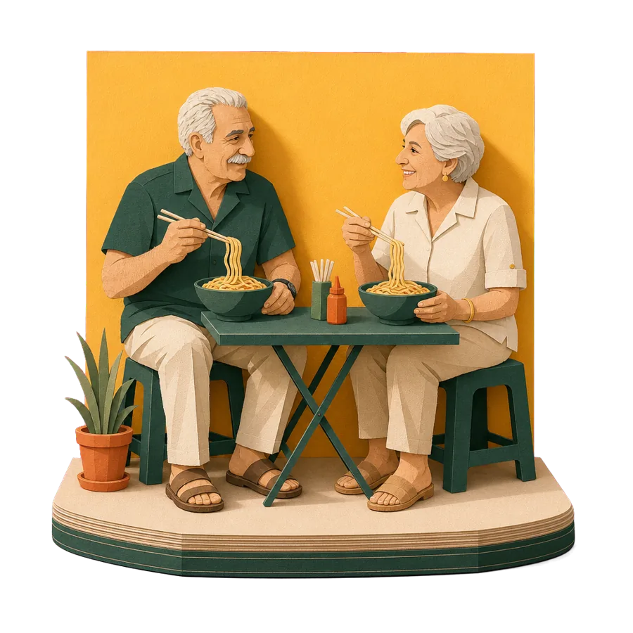 A retired couple eat bowls of noodles on low stools at a street table, for the cost of a month in Hoi An
