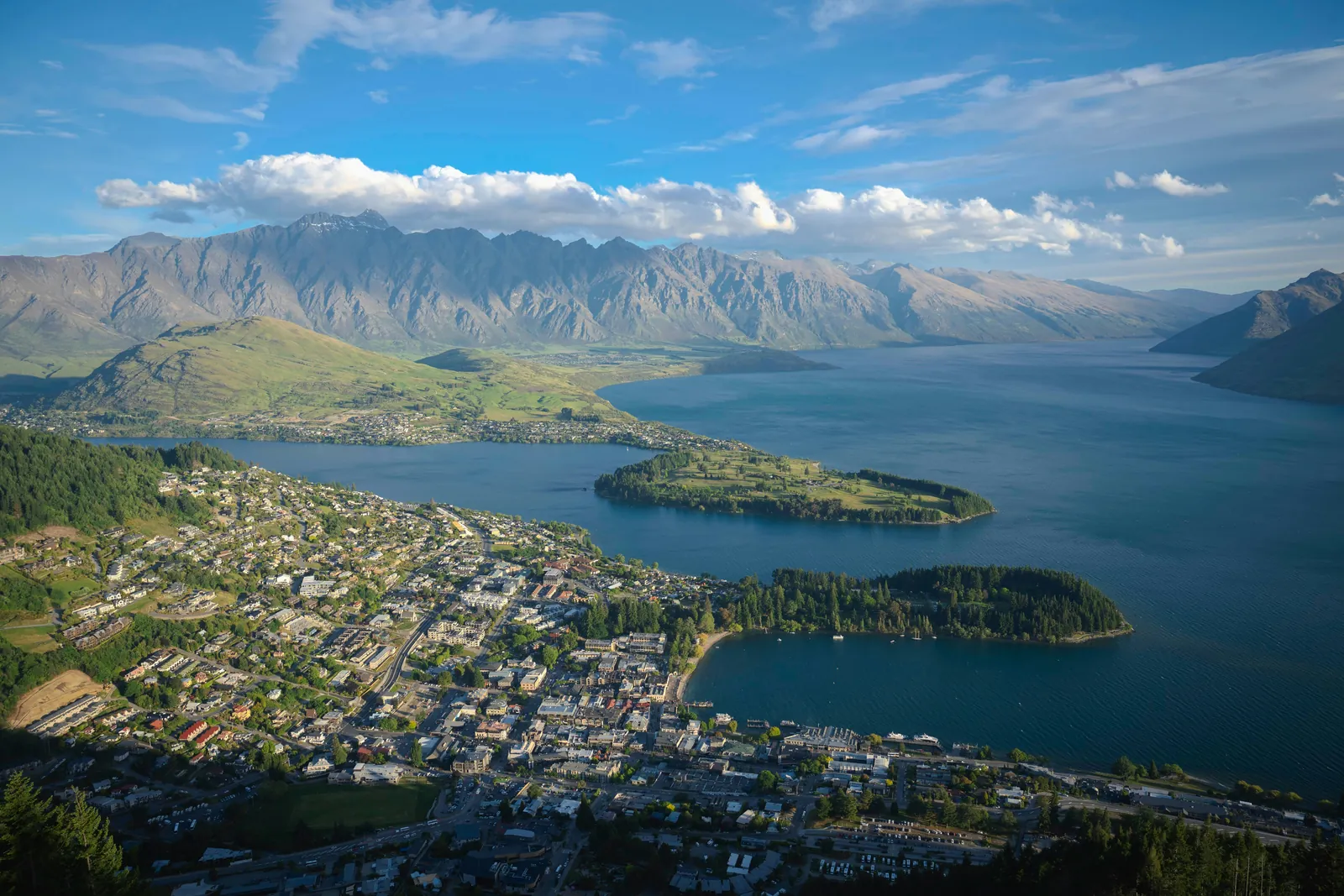 Queenstown spread along the shore of Lake Wakatipu, with tree-covered peninsulas in the lake and the jagged Remarkables range behind